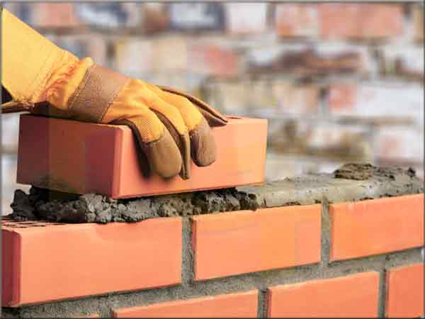 albanil tapiando pared con ladrillo y cemento